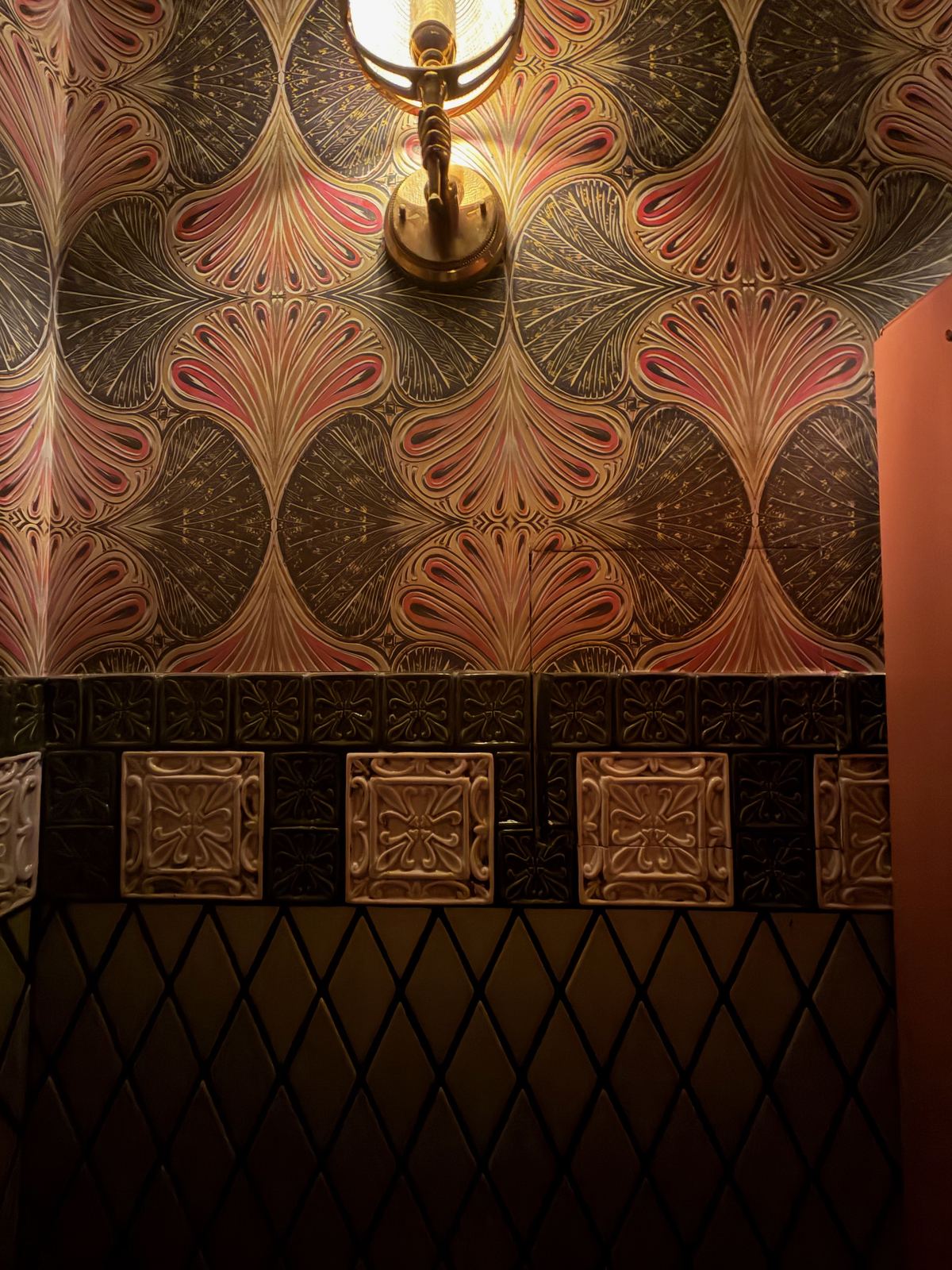 Ornate art-nouveau wallpaper and a brass sconce, evoking an old law office